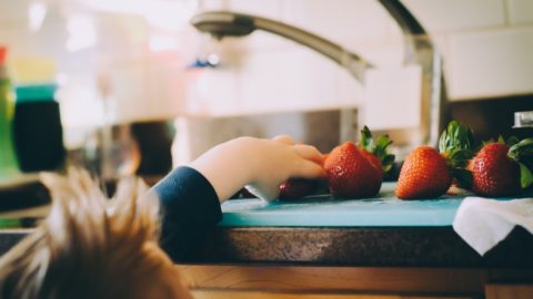 A kid is trying to take strawberry from the table