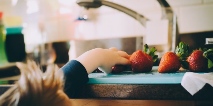 A kid is trying to take strawberry from the table