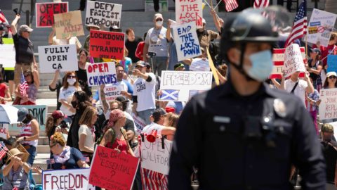 People in front of Los Angeles’ City Hall protest the state’s COVID-19 stay-at-home orders in May.