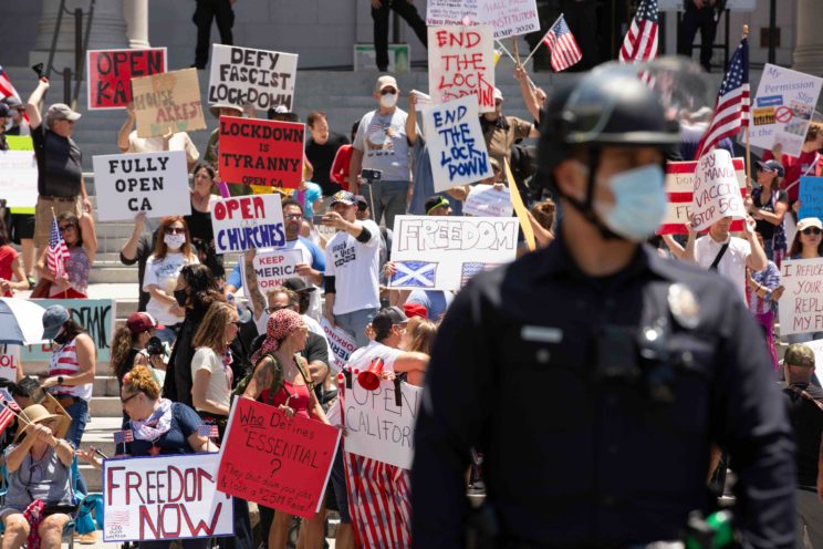 People in front of Los Angeles’ City Hall protest the state’s COVID-19 stay-at-home orders in May.