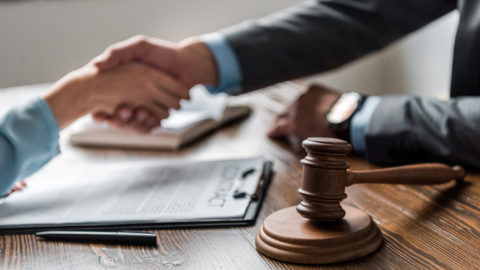 gavel in foreground of client and attorney shaking hands