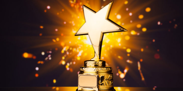 gold star trophy against shiny sparks background