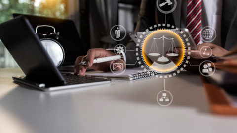 A lawyer is working on document with an iPad and laptop.