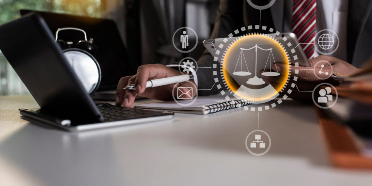 A lawyer is working on document with an iPad and laptop.