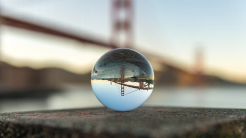 San Francisco Golden Gate Bridge in the background with its reflection inside a crystal ball in the center