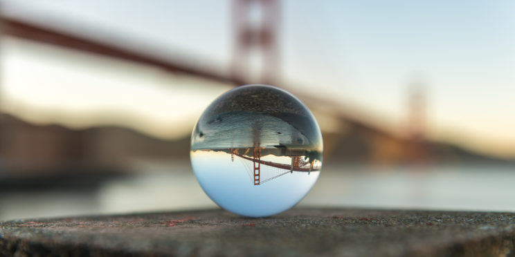 San Francisco Golden Gate Bridge in the background with its reflection inside a crystal ball in the center