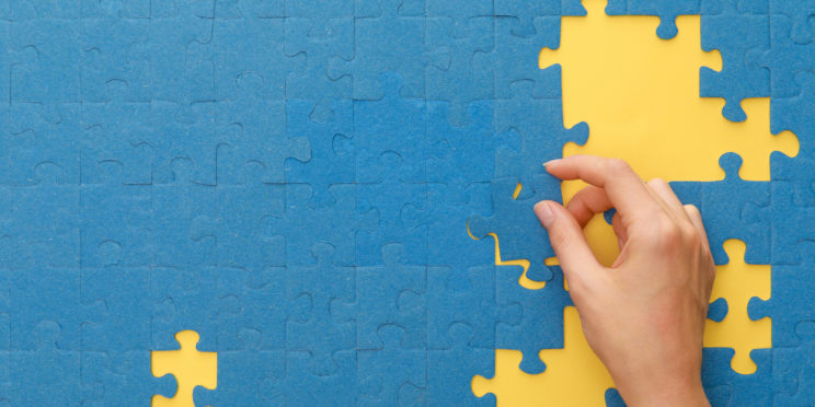 crop-view of a person's hand matching a blue puzzle on background