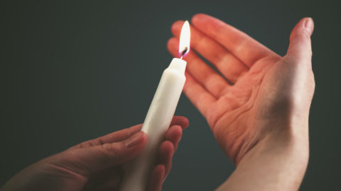 Female hands with burning candle in the dark
