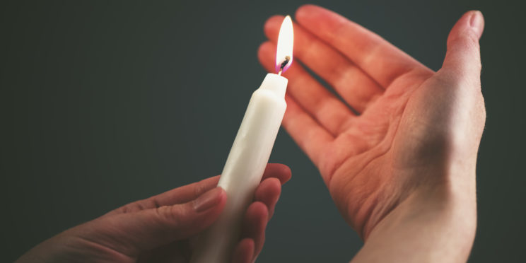 Female hands with burning candle in the dark