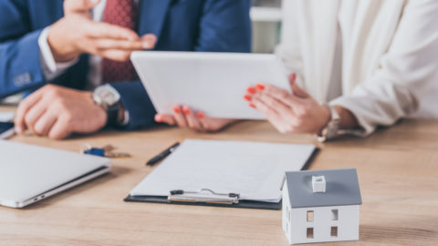 Selective focus of house model near woman holding digital tablet and businessman pointing with hand