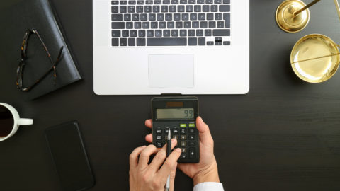 Lawyer is using calculator with scale and laptop on the desk.