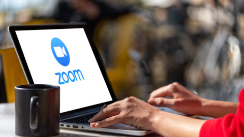 Woman using laptop showing Zoom Cloud Meetings app logo