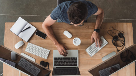 Overhead view of programmer using computers at workplace