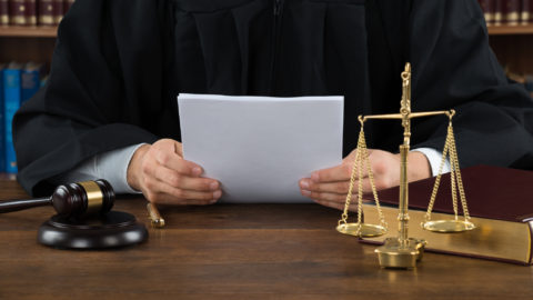 Judge Reading Documents At Desk In Courtroom