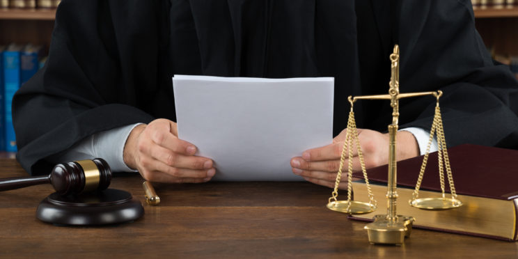 Judge Reading Documents At Desk In Courtroom