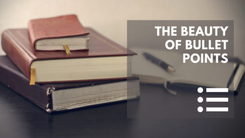 A stack of antique books and a pen and notebook on the desk