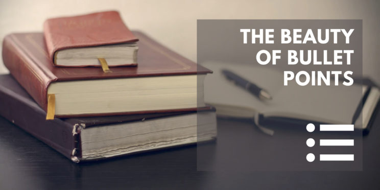 A stack of antique books and a pen and notebook on the desk