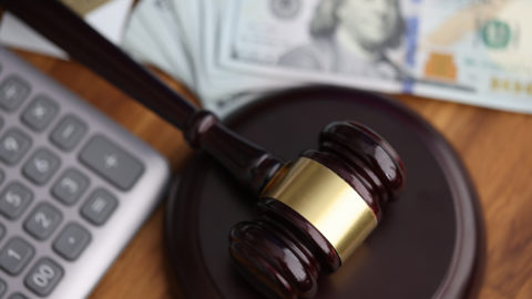 Hammer, american dollars, calculator lie on table in courthouse close-up. Illegal decisions of lawsuits concept.