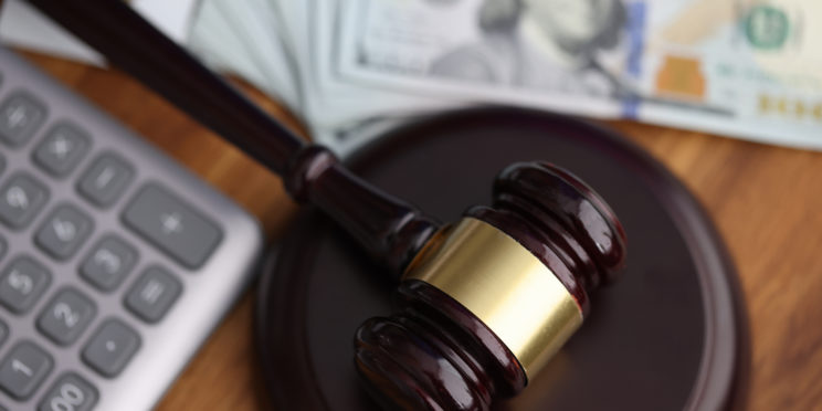 Hammer, american dollars, calculator lie on table in courthouse close-up. Illegal decisions of lawsuits concept.