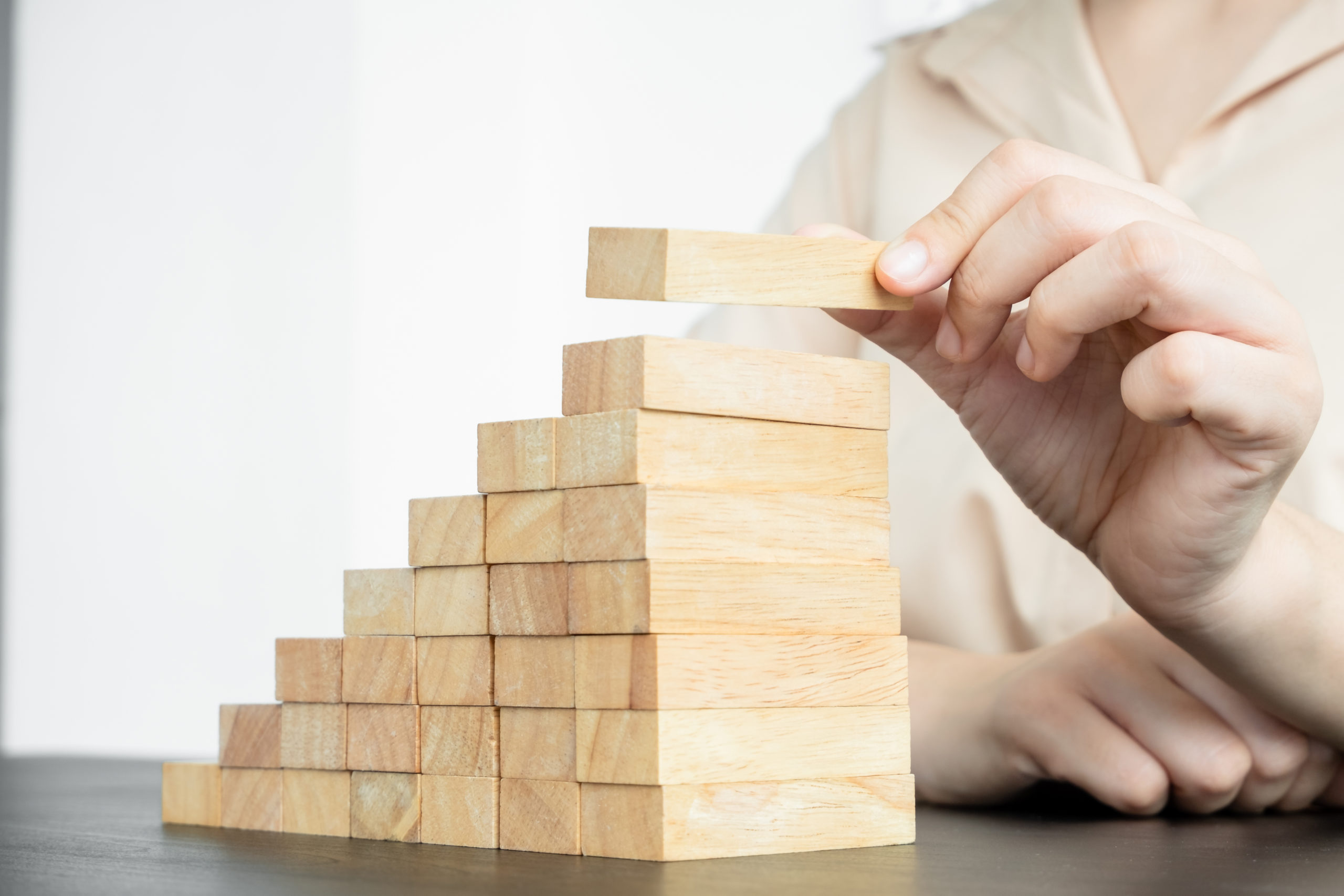 Hands of businesswomen playing wooden block game. Concept Risk of management and strategy plans for business growth and success.