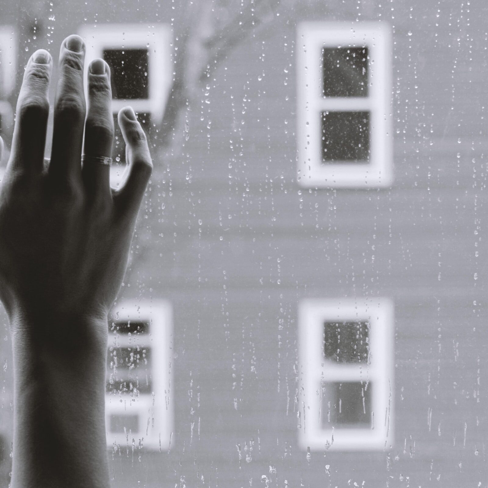 Woman with ring stands next to the window looking at the apartment across